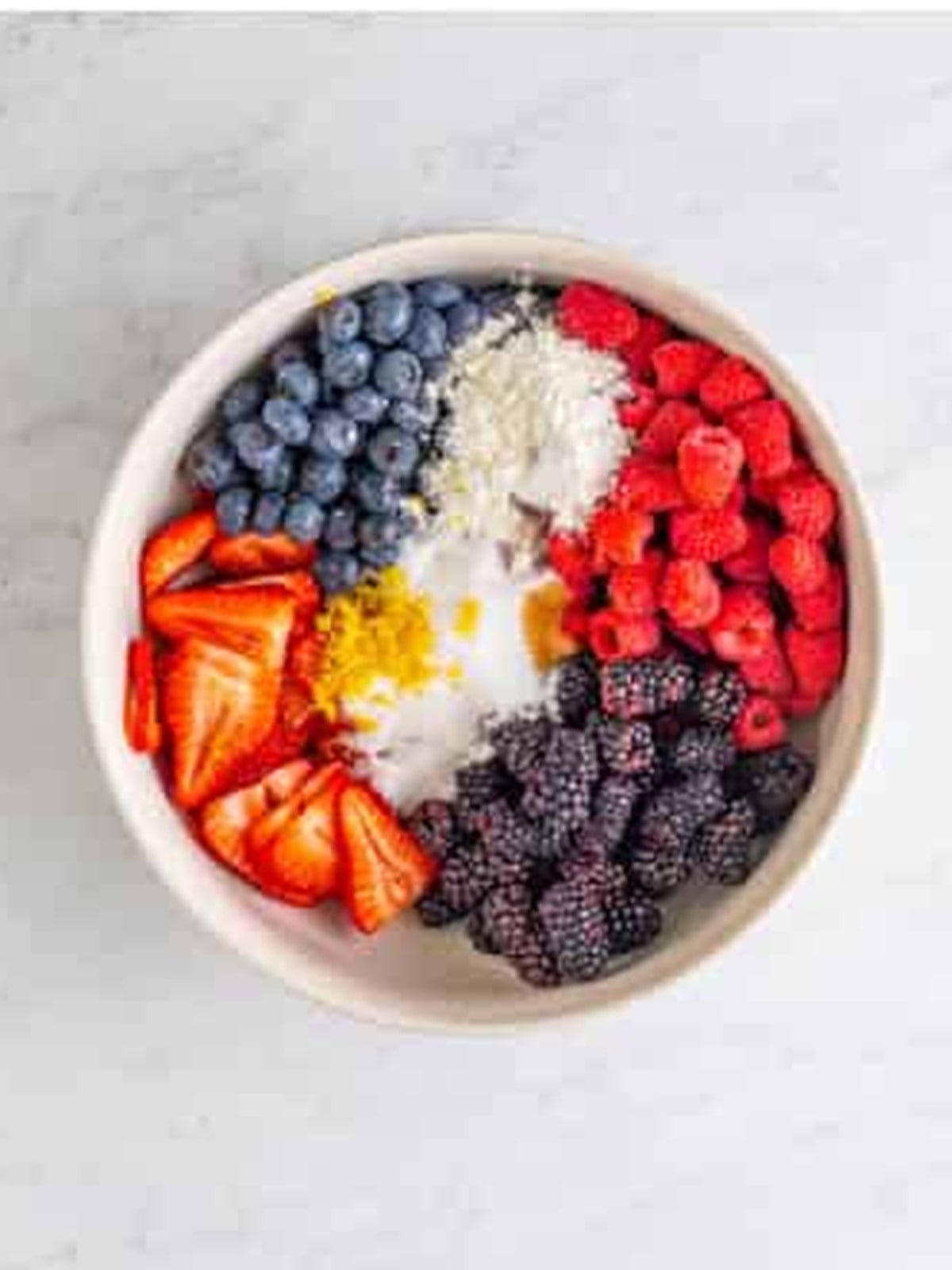 Mixed berries tossed with sugar, cornstarch, and lemon in a bowl for berry cobbler.