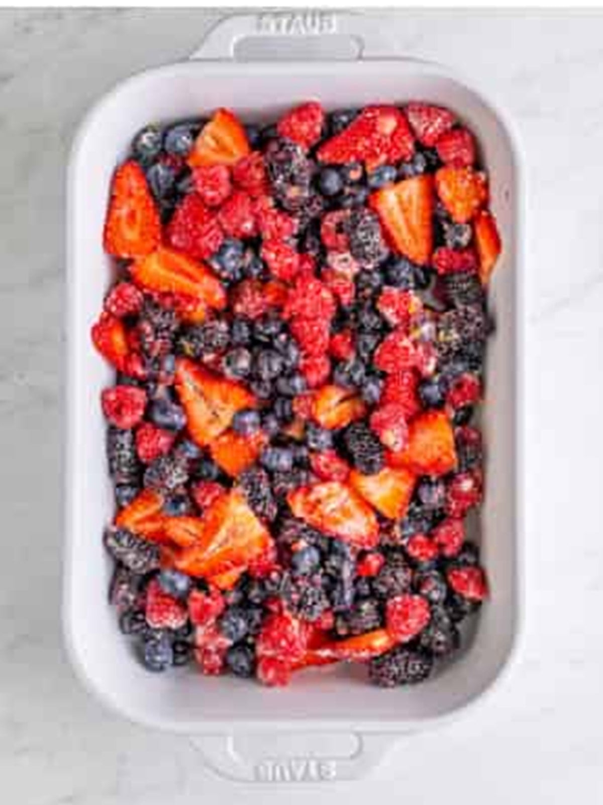 Berry filling spread in a white baking dish for berry cobbler.