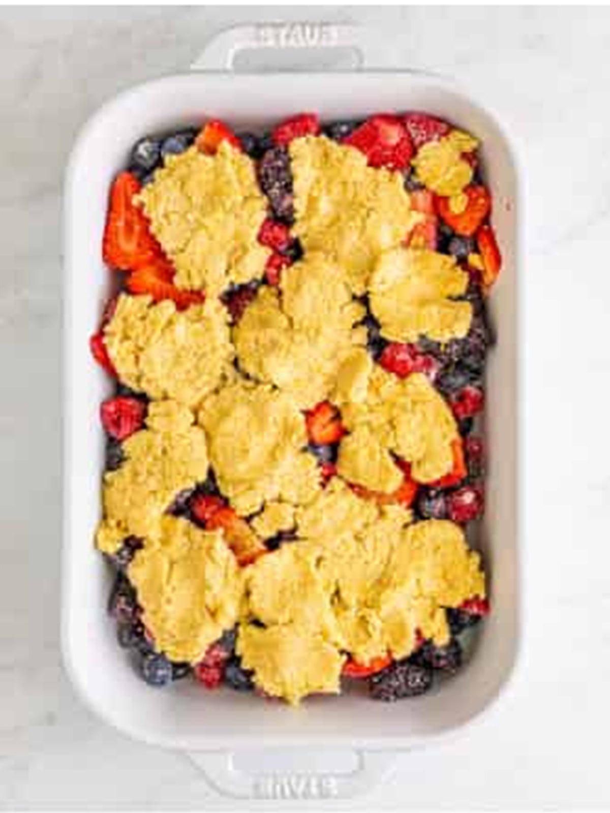 Dropping the crumbly biscuit topping over the berries for cobbler.