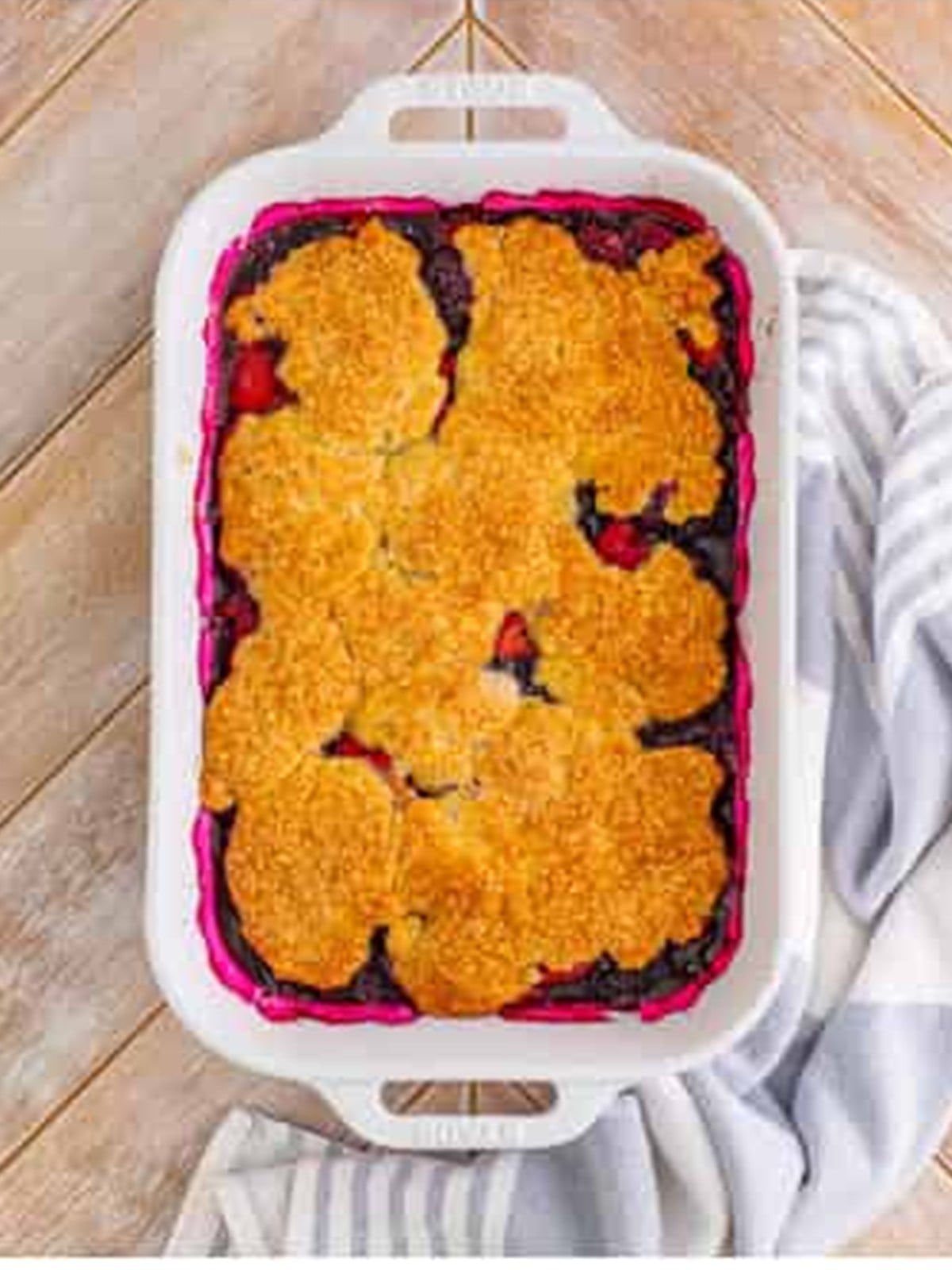 Golden baked berry cobbler bubbling in a white baking dish.