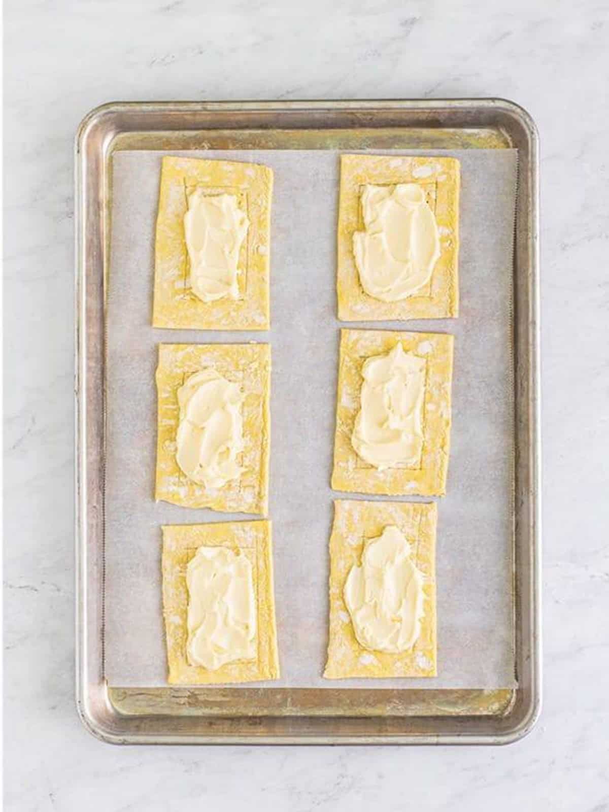 Cream cheese filling spread in the center of each puff pastry rectangle for berry danish.