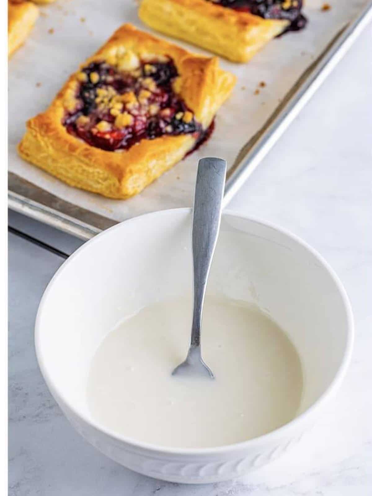 Powdered sugar glaze whisked smooth for drizzling over berry danish.