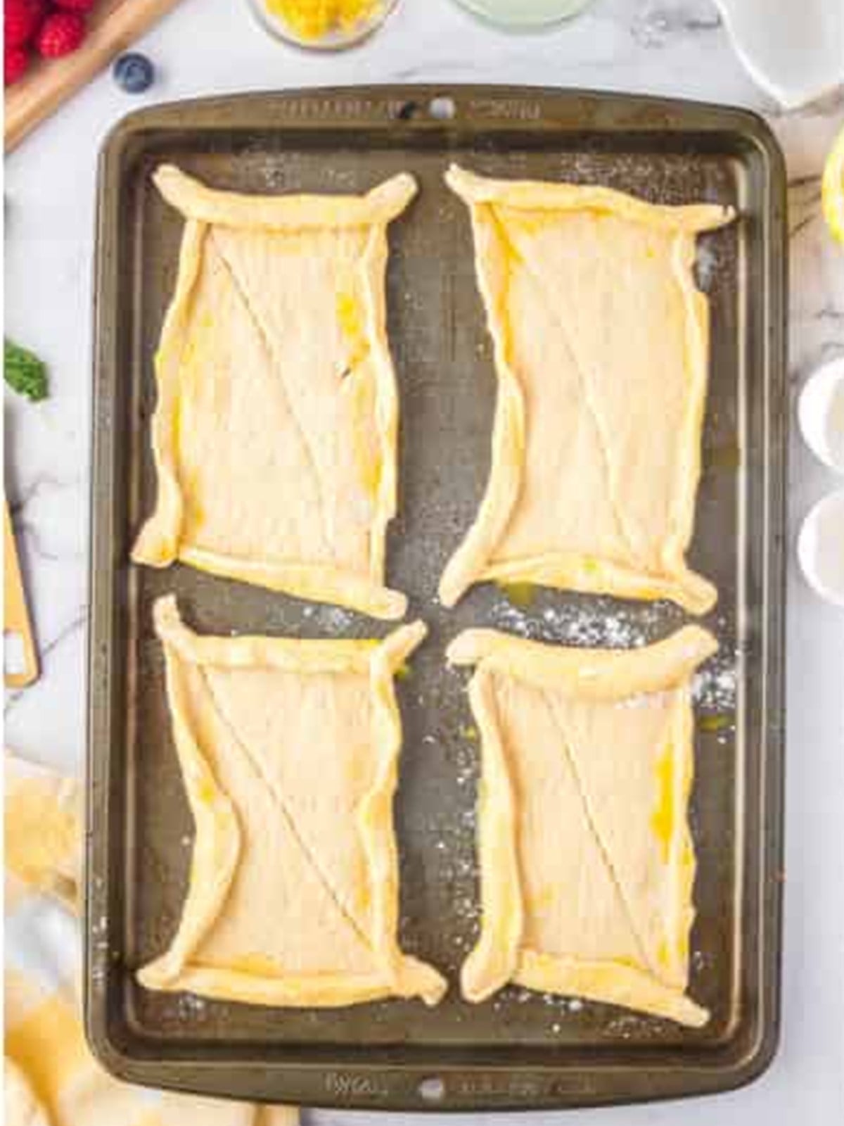 Crescent dough shaped into rectangular tart shells with rolled borders on a tray.