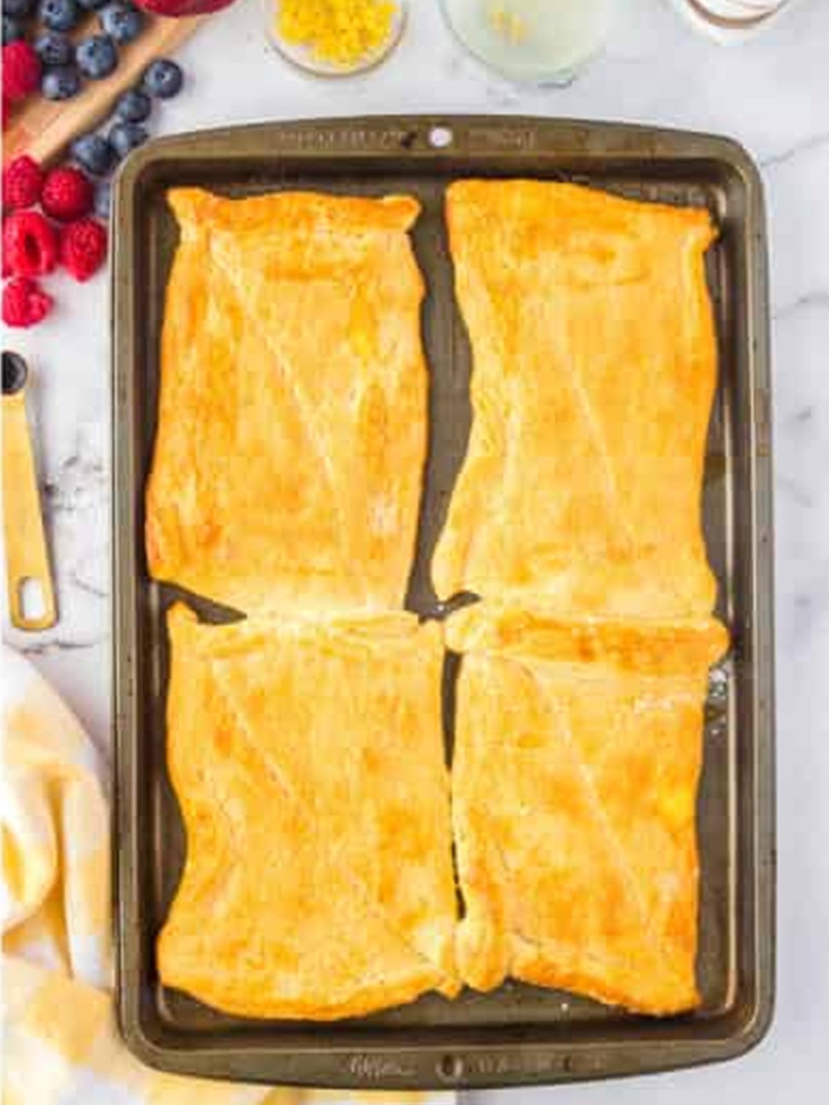 Golden baked crescent dough tart shells on a baking sheet.