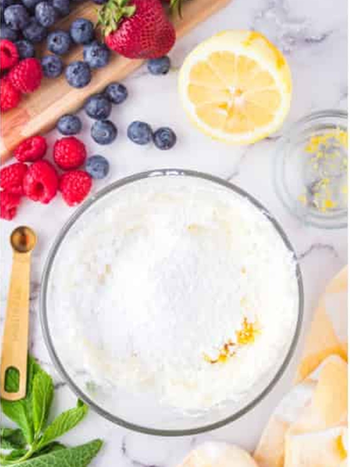 Powdered sugar, lemon, and vanilla added to cream cheese in a bowl.