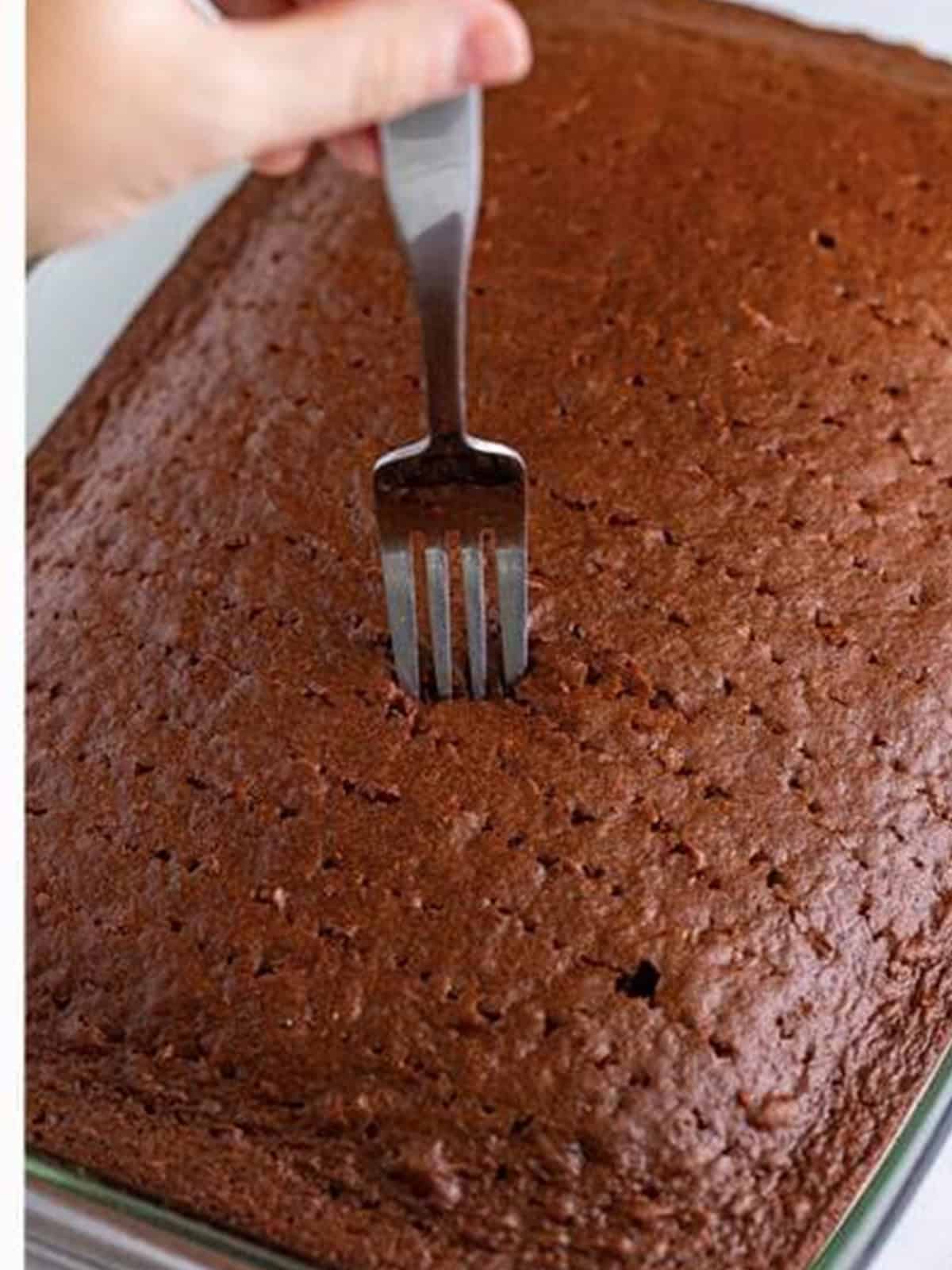 Poking holes in the baked cake with a fork