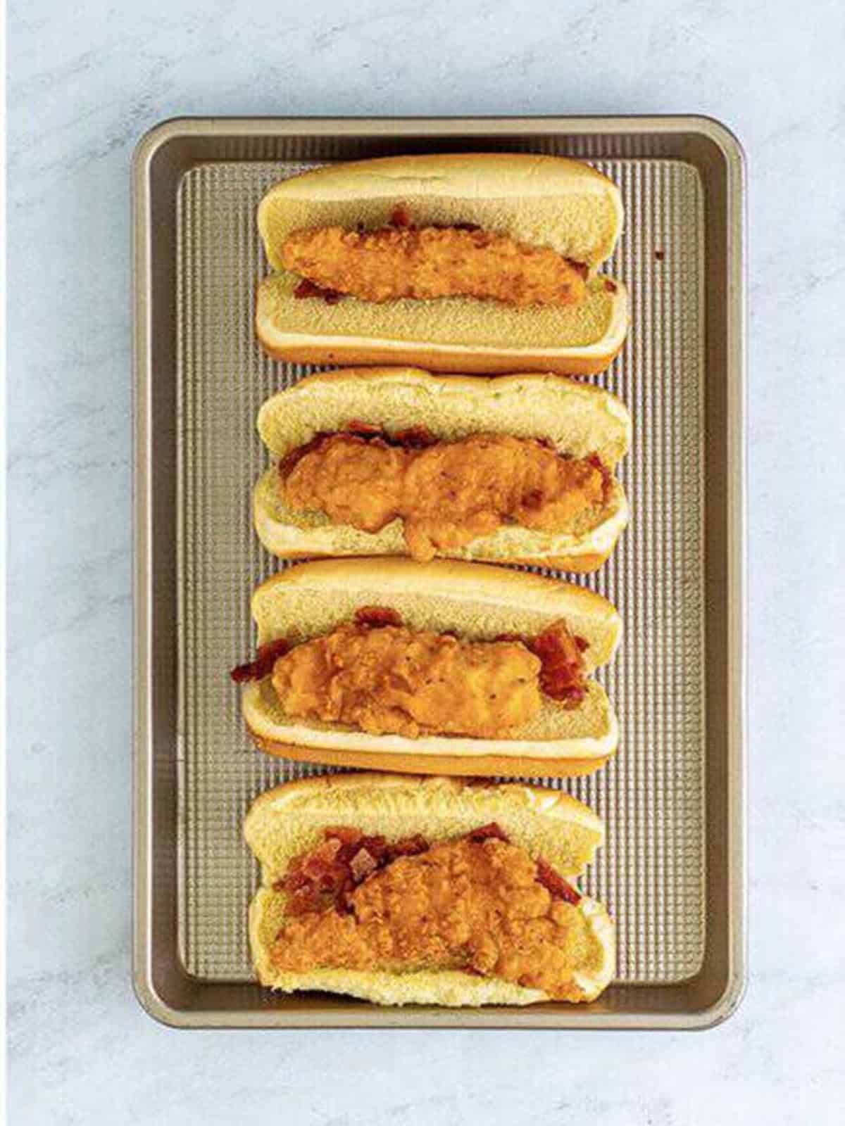 A crispy breaded chicken tender placed in each bacon-lined bun.