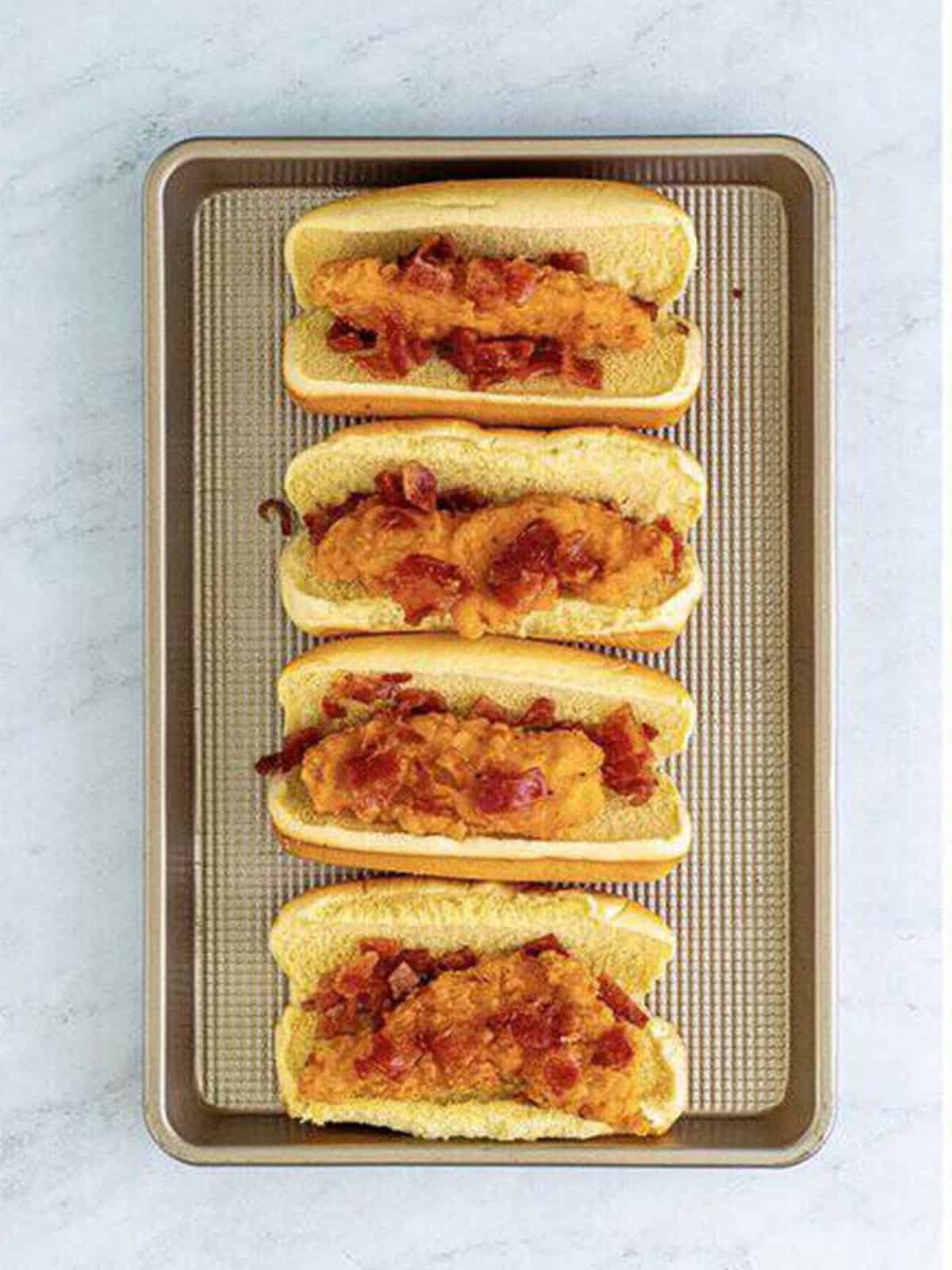 More crumbled bacon added on top of the chicken tenders in the buns.