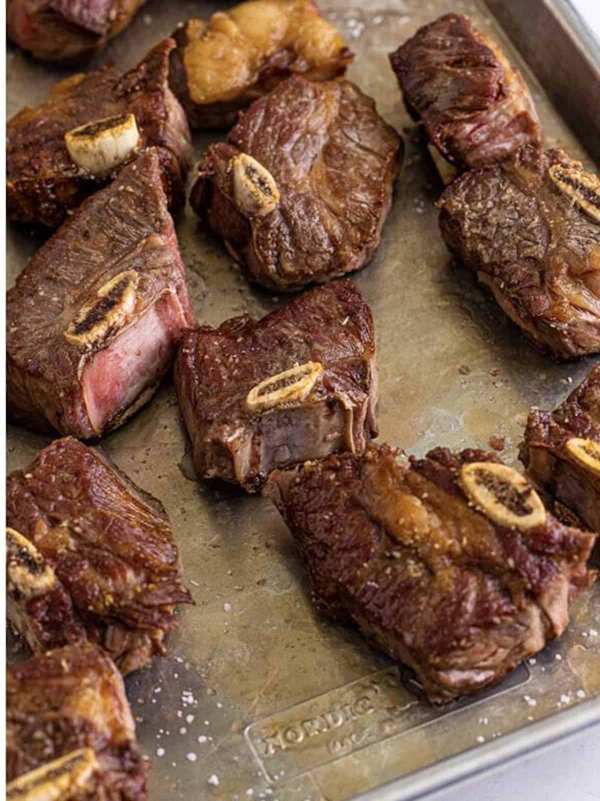 Beef short ribs seared golden brown on a sheet tray for birria.