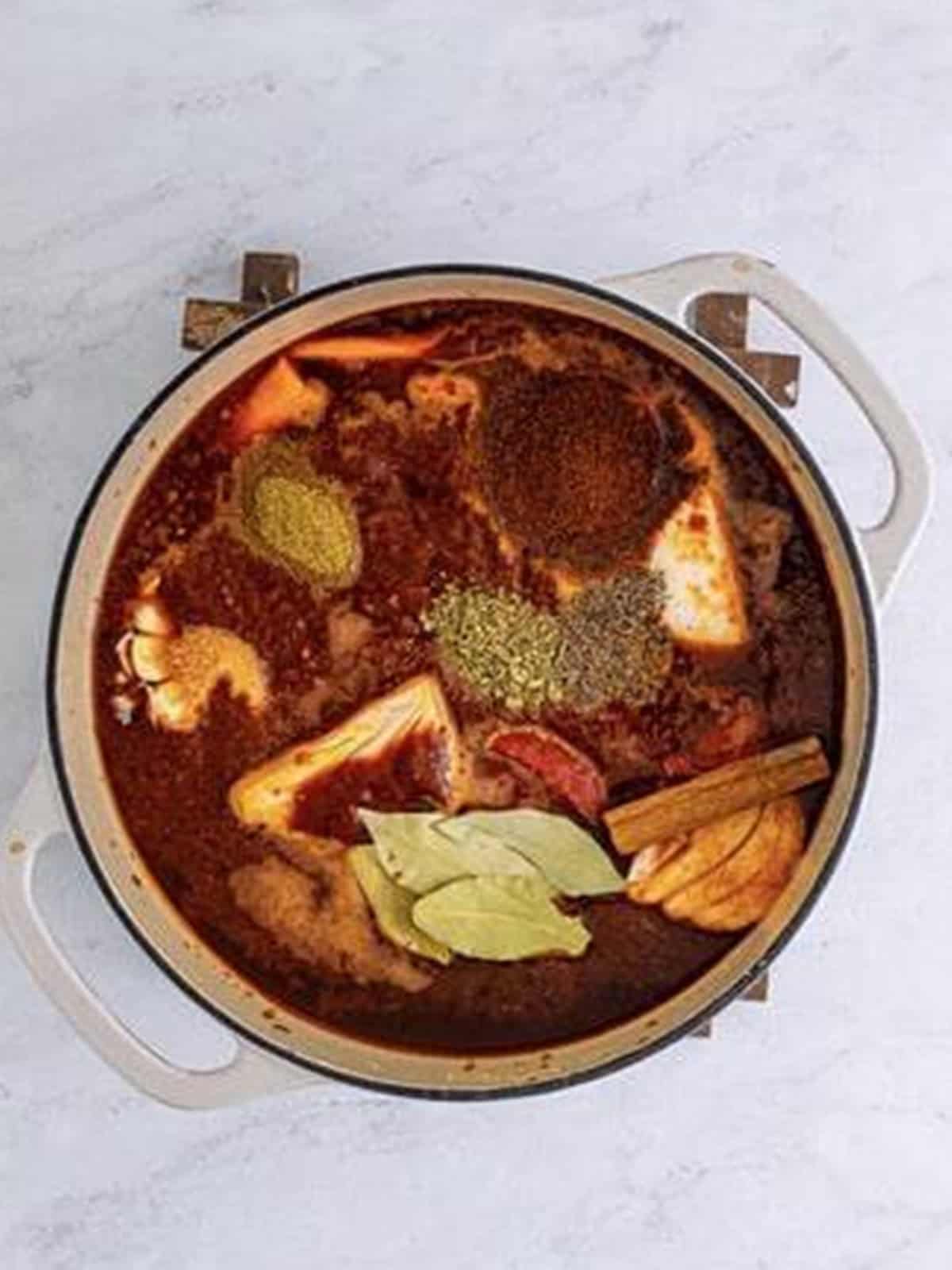 Spices, bay leaves, and aromatics added to the birria braising pot.