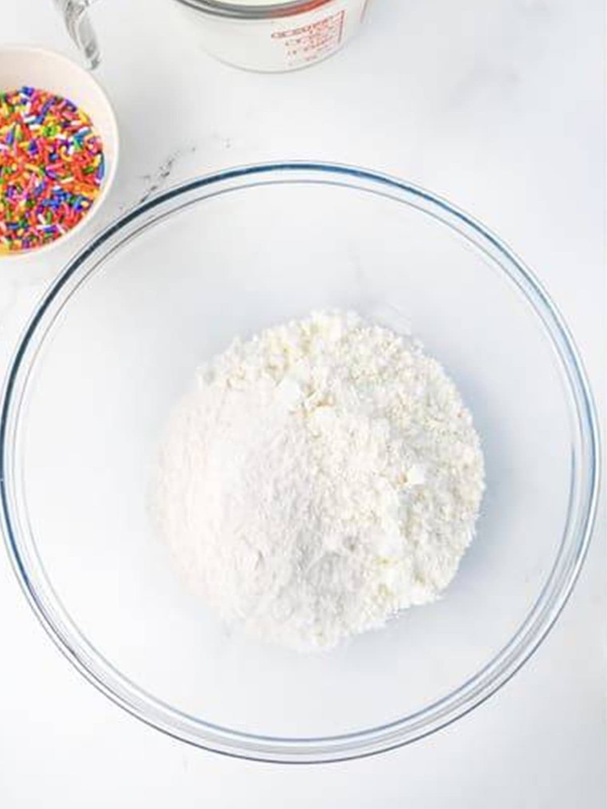 Whisking together vanilla pudding mix and white cake mix in a glass bowl.