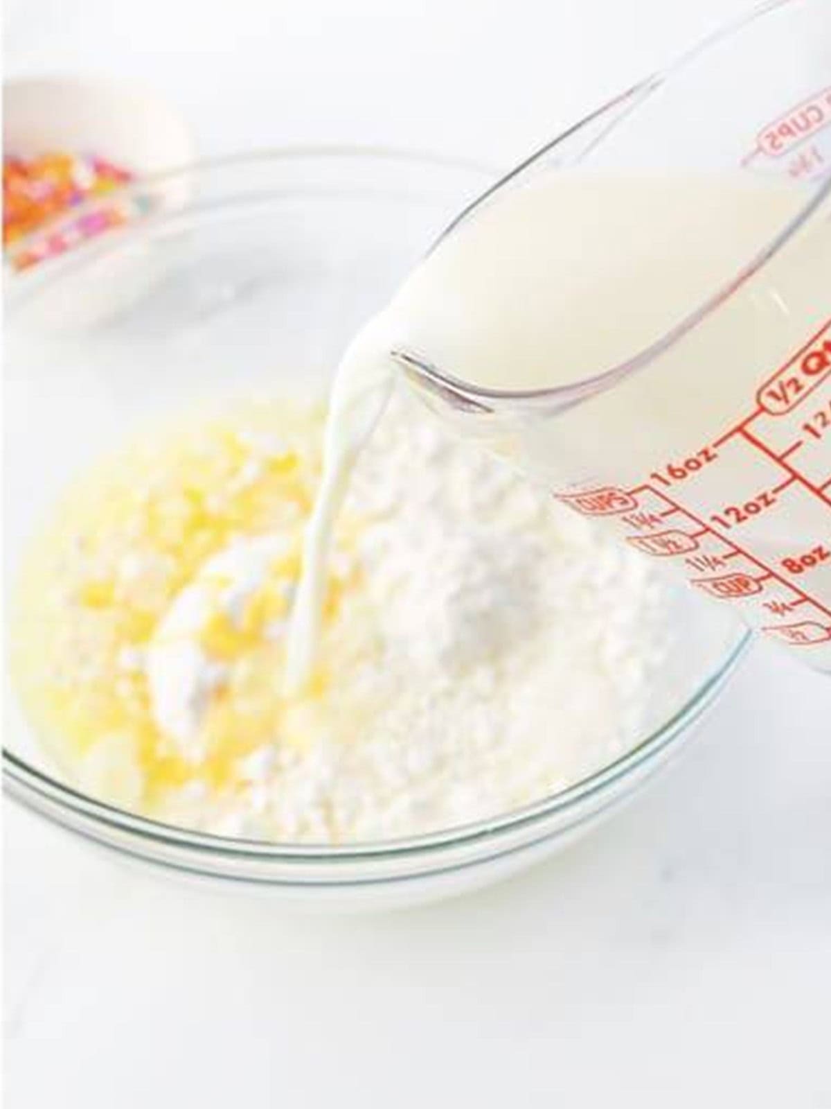 Pouring milk into the pudding and cake mix and whisking until smooth.