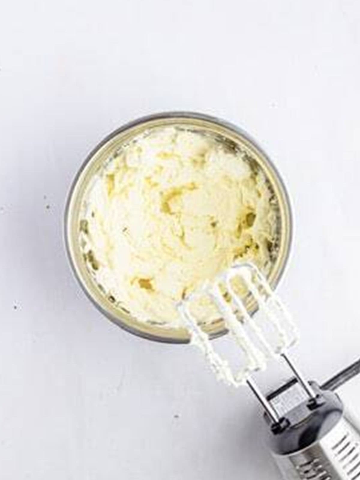 Cream cheese and sugar beaten until smooth in a bowl for Biscoff cheesecake bars.
