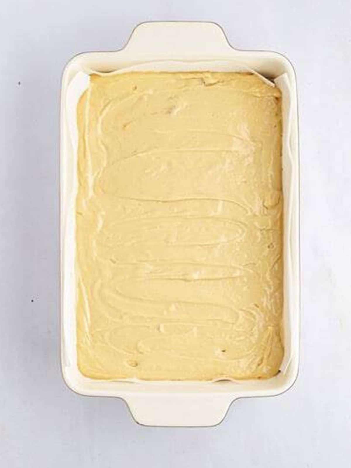 Biscoff cheesecake filling spread over the cookie crust in a baking dish.