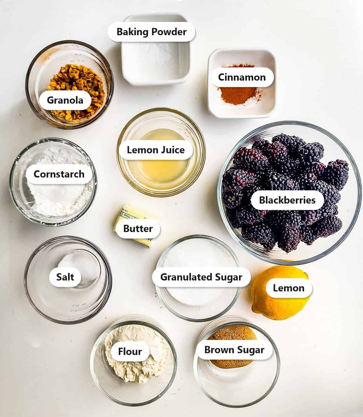 Labeled ingredients for blackberry crisp including blackberries, sugars, cornstarch, flour, butter, granola, lemon, and cinnamon.