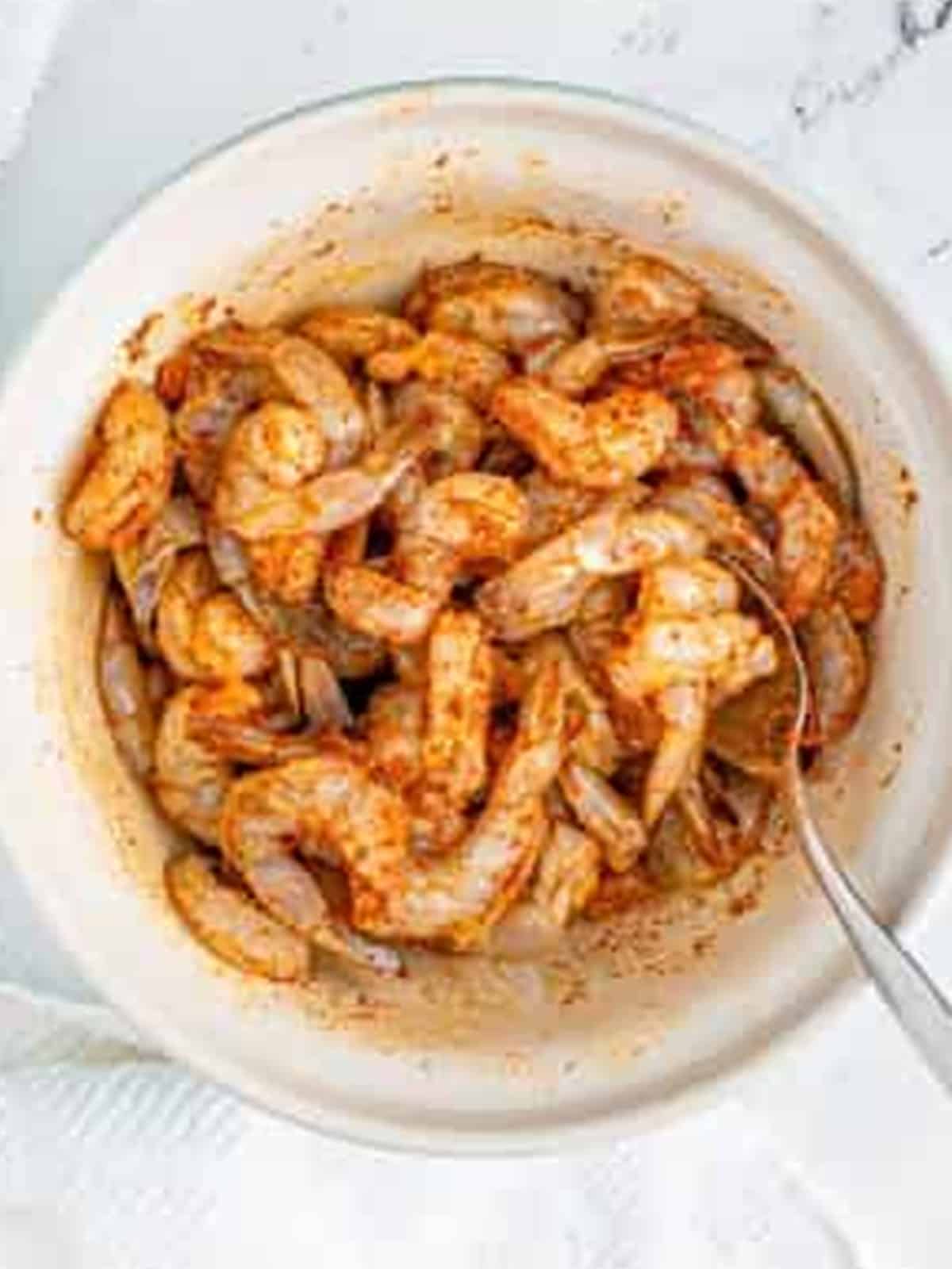 Tossing shrimp in oil and blackening seasoning until well coated for Blackened Shrimp.