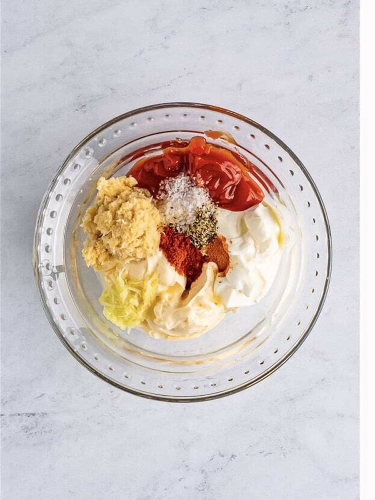 Mayonnaise, sour cream, ketchup, horseradish, garlic, and spices combined in a glass bowl to make Bloomin Onion Sauce.