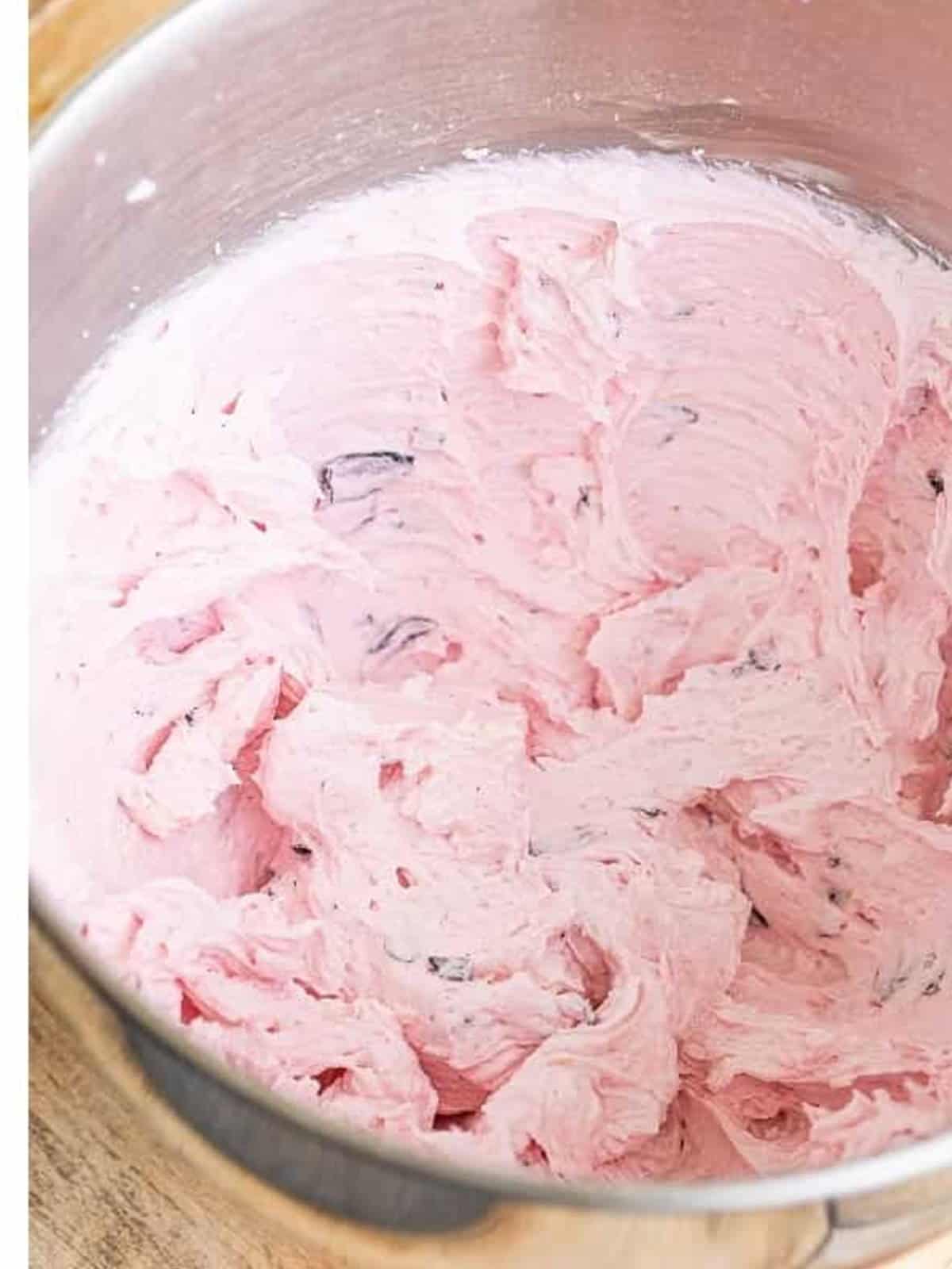 Light and fluffy pink blueberry frosting in a mixing bowl.