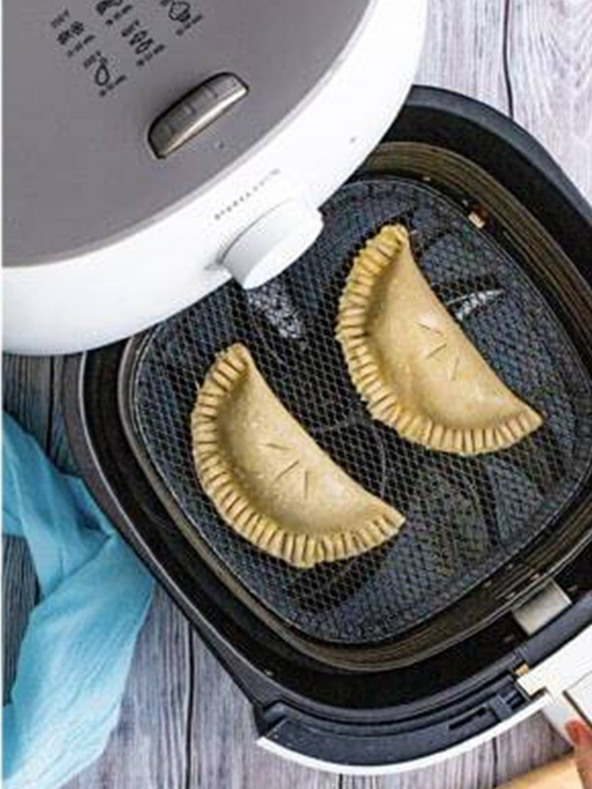 Blueberry hand pies arranged in an air fryer basket.