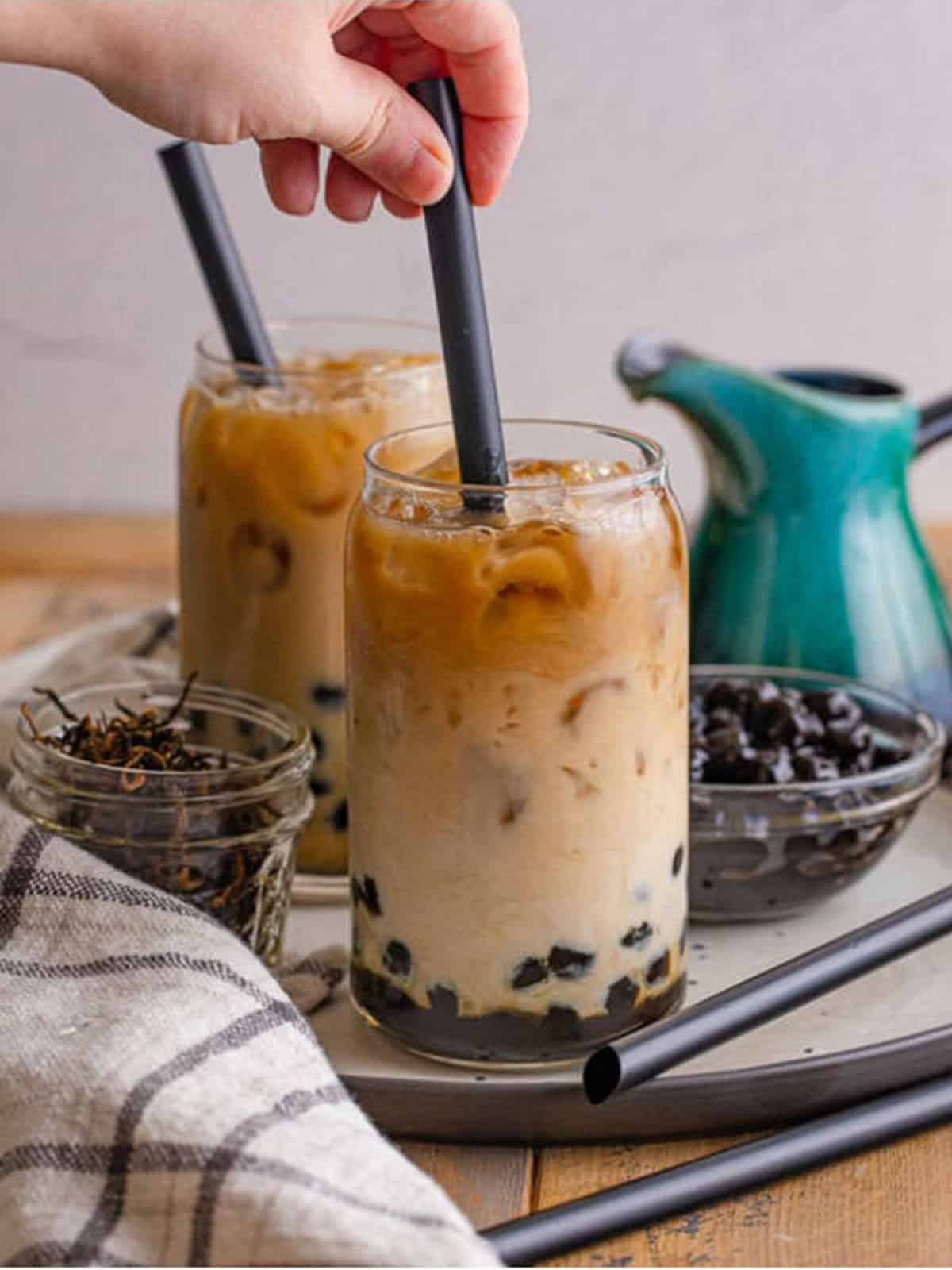 Two finished glasses of boba tea with tapioca pearls and straws