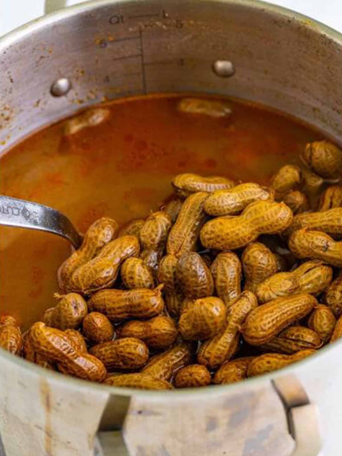 Boiled peanuts lifted with a ladle to check tenderness while simmering.