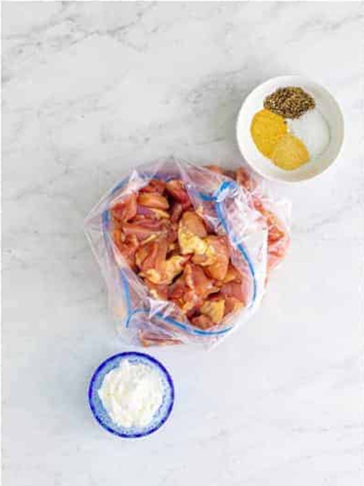 Bite-sized chicken thighs tossed with cornstarch and seasonings in a bag for bourbon chicken.