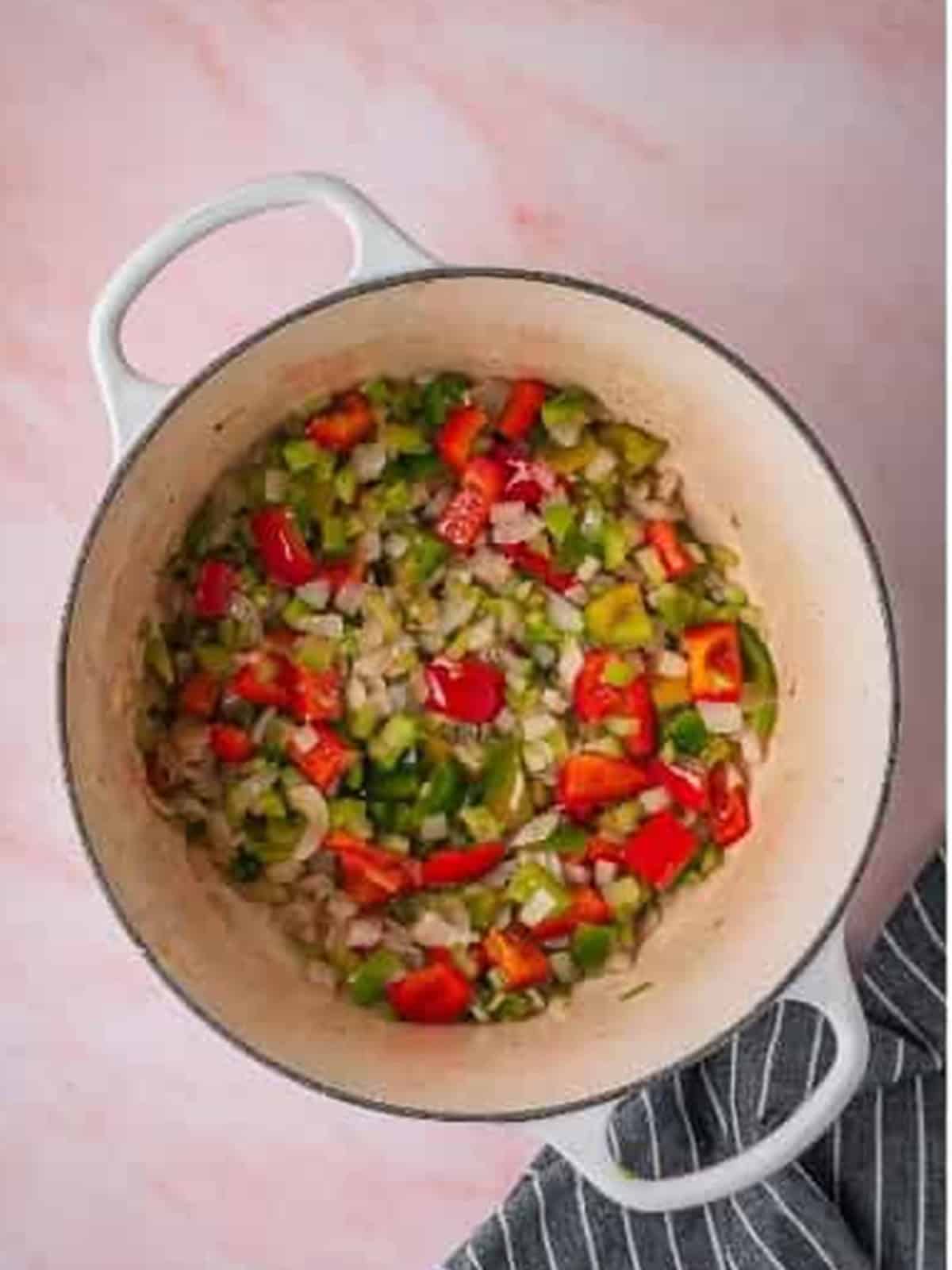 Diced vegetables sauteing in a Dutch oven until softened.