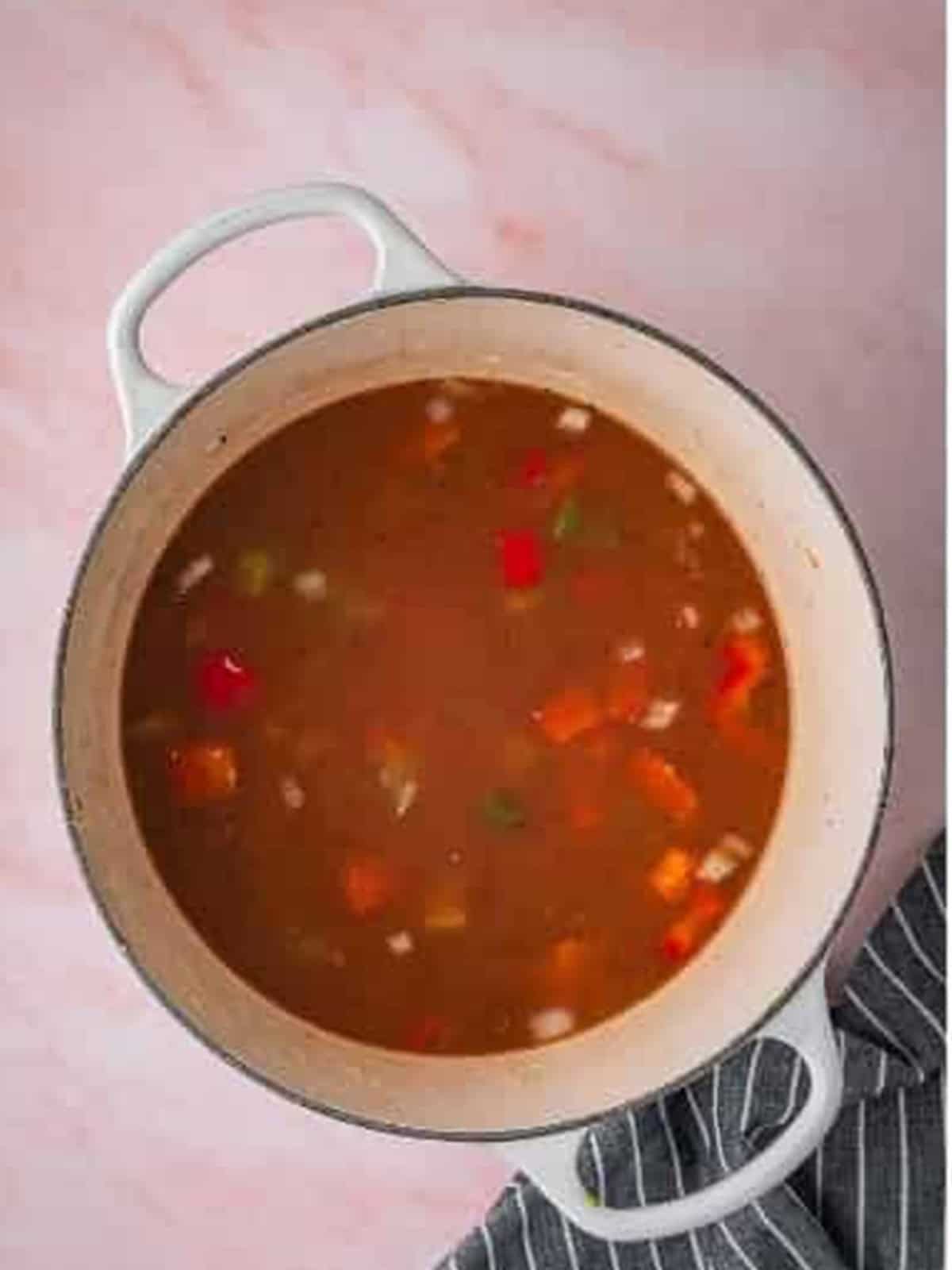 Beef broth whisked into the vegetables and flour in a Dutch oven.
