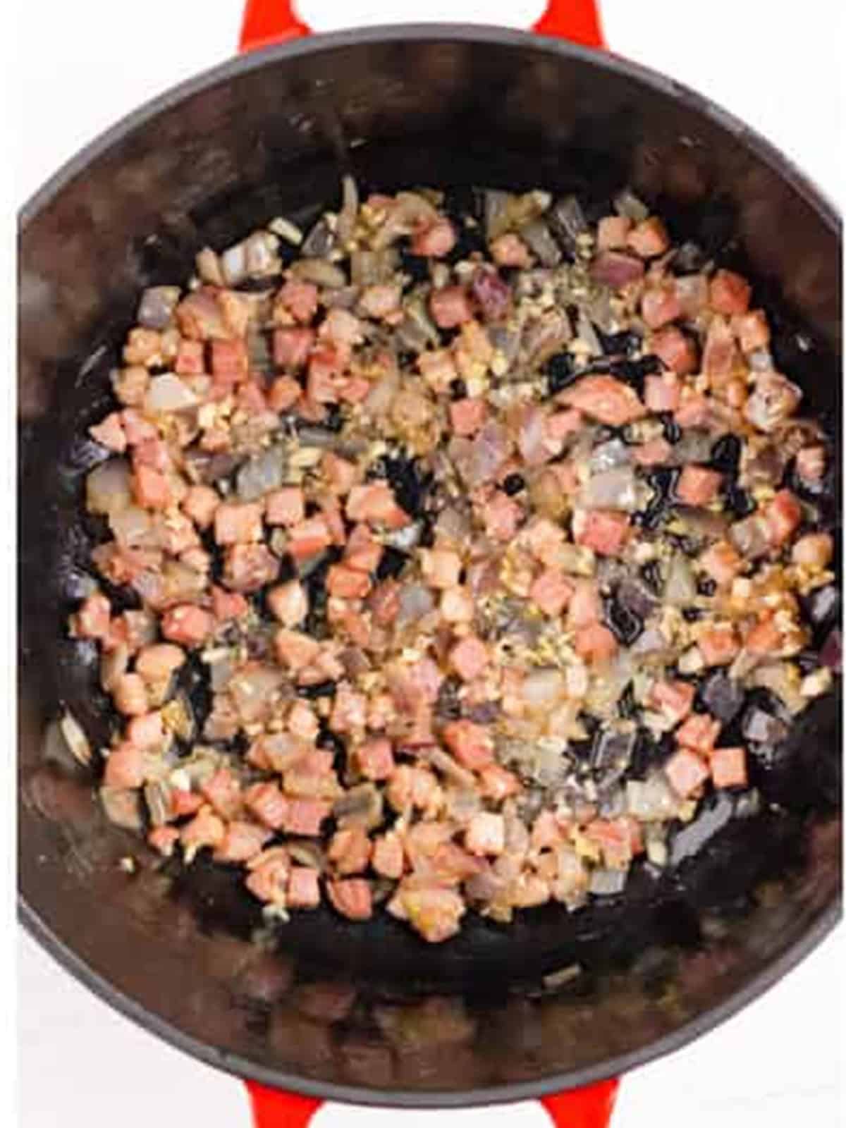 Pancetta, onion, and garlic cooking in a Dutch oven for braised short ribs.