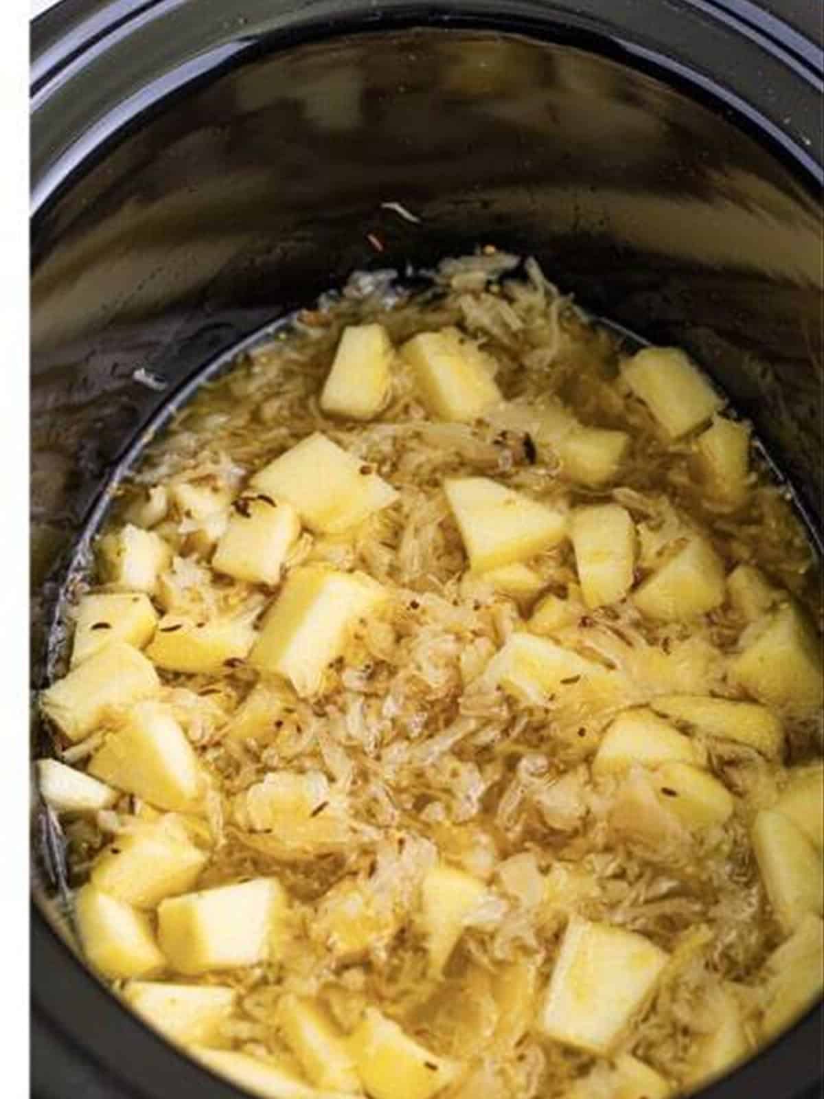 Mixed sauerkraut and apple in the slow cooker for brats and sauerkraut.