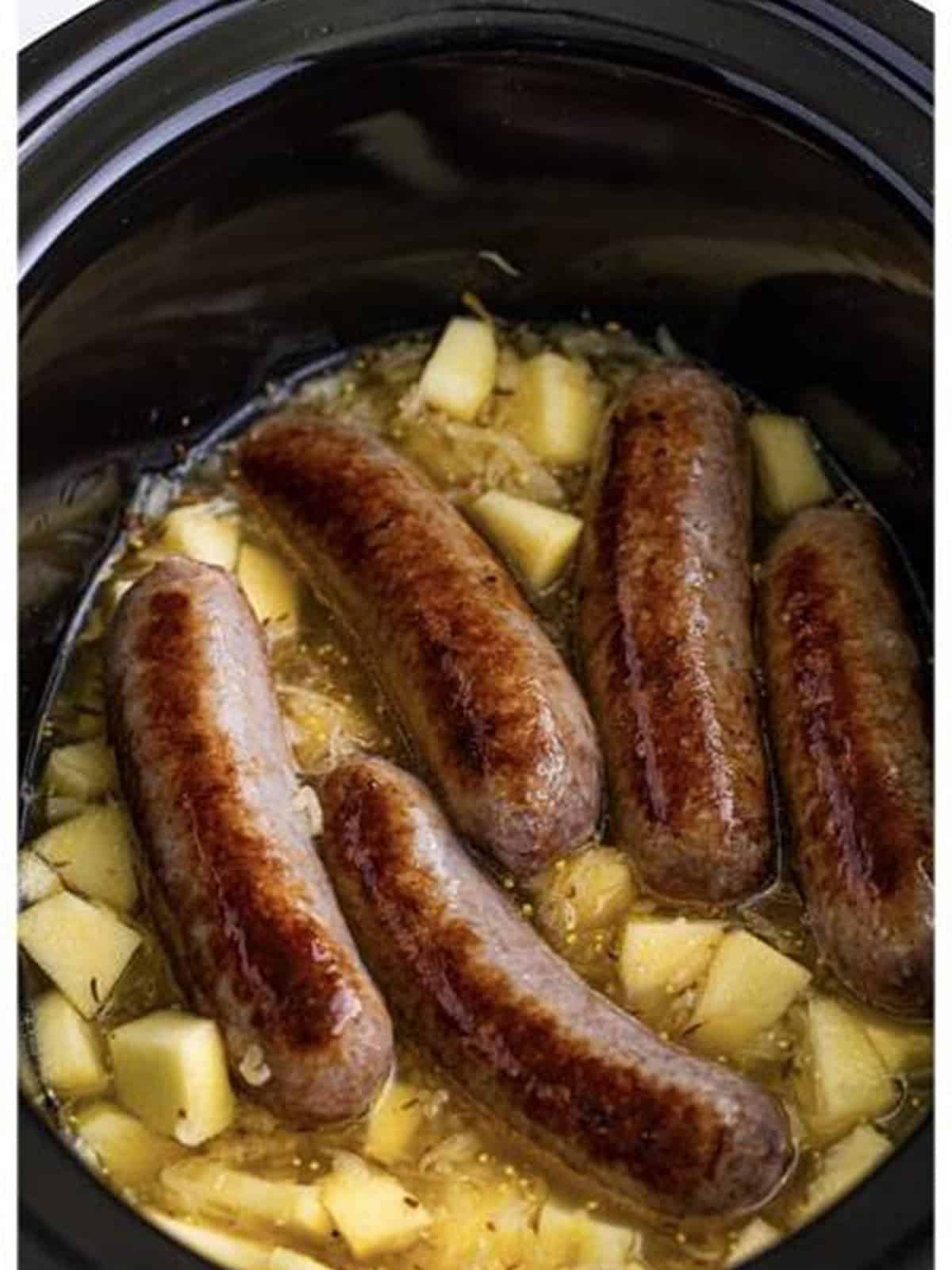 Bratwurst nestled into the sauerkraut in the slow cooker.