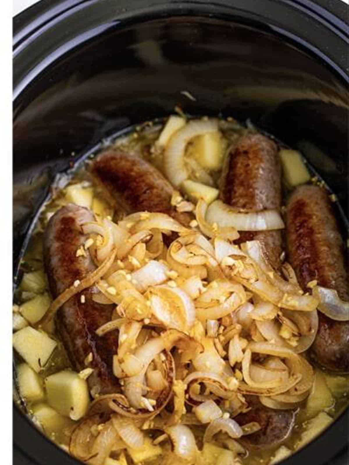 Brats and sauerkraut topped with sauteed onions in the slow cooker.
