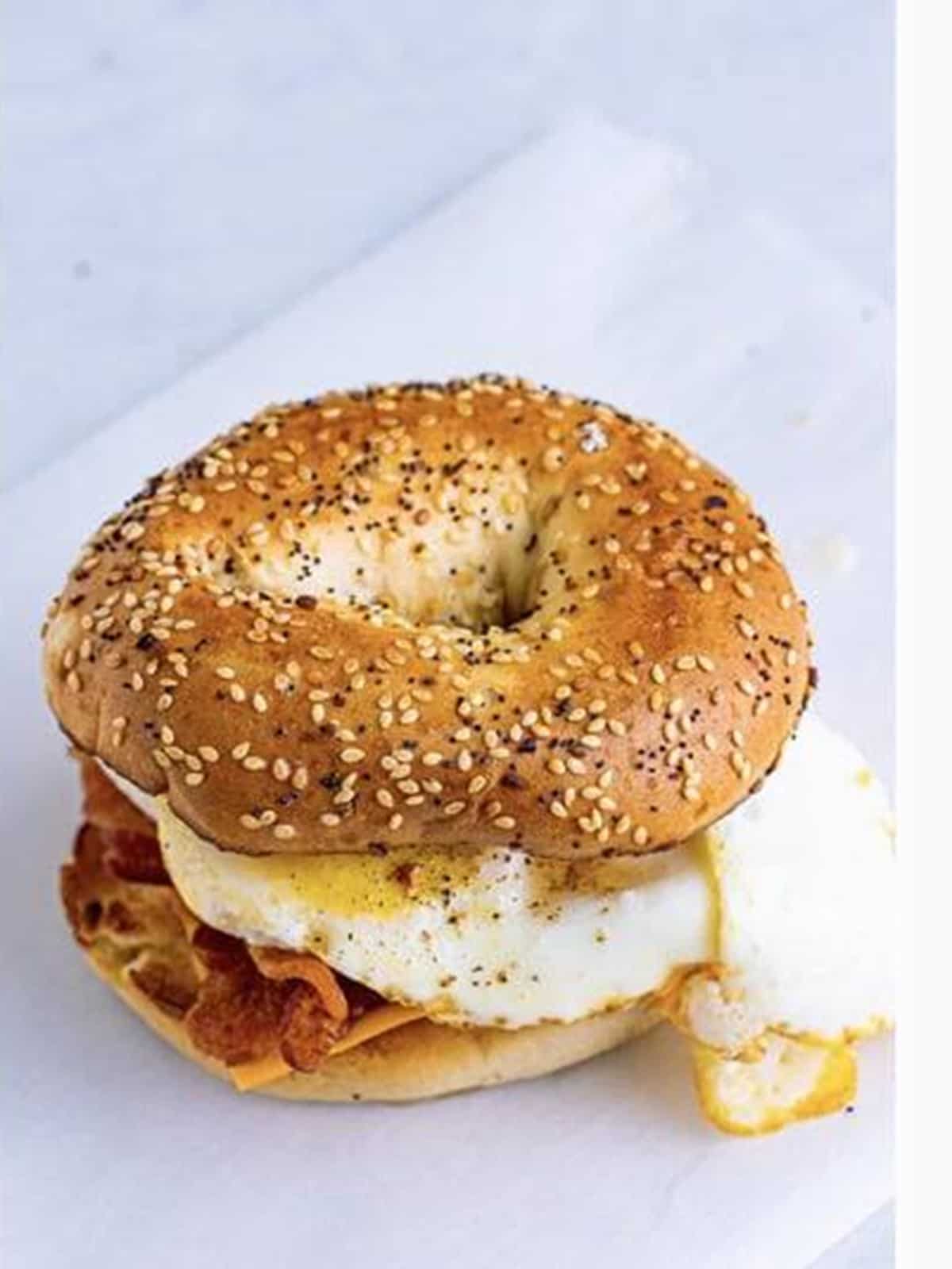 The assembled breakfast bagel sandwich crowned with the toasted bagel top.