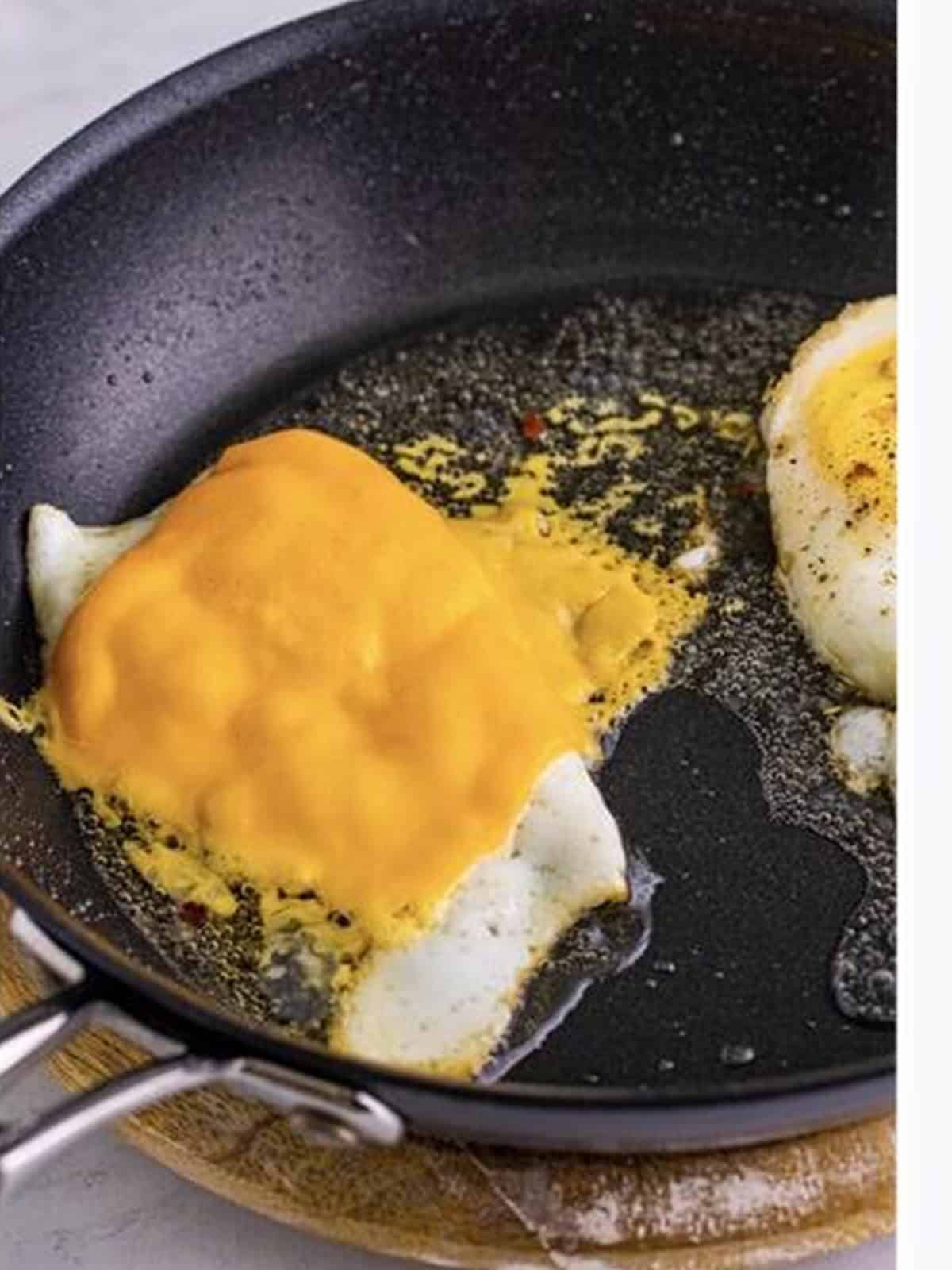 American cheese melting over the fried egg in the covered skillet.