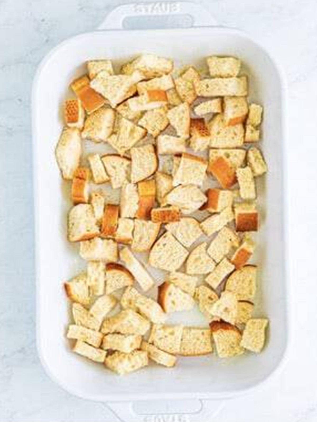 Cubed crusty bread layered in a baking dish for breakfast casserole