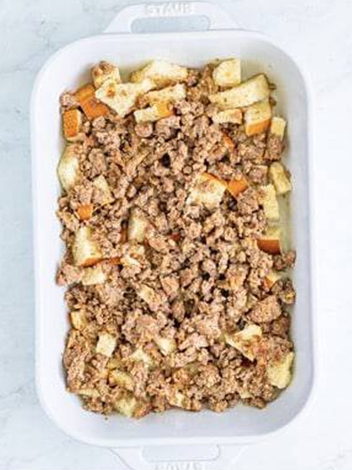 Cooked breakfast sausage layered over bread in breakfast casserole