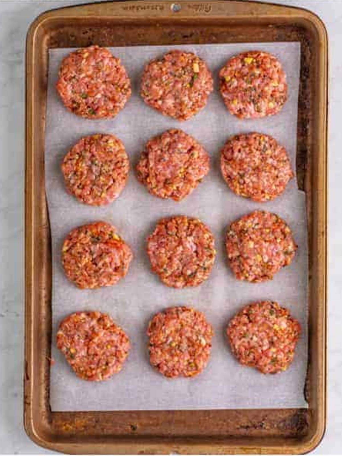 Raw breakfast sausage portioned into patties on a sheet tray.