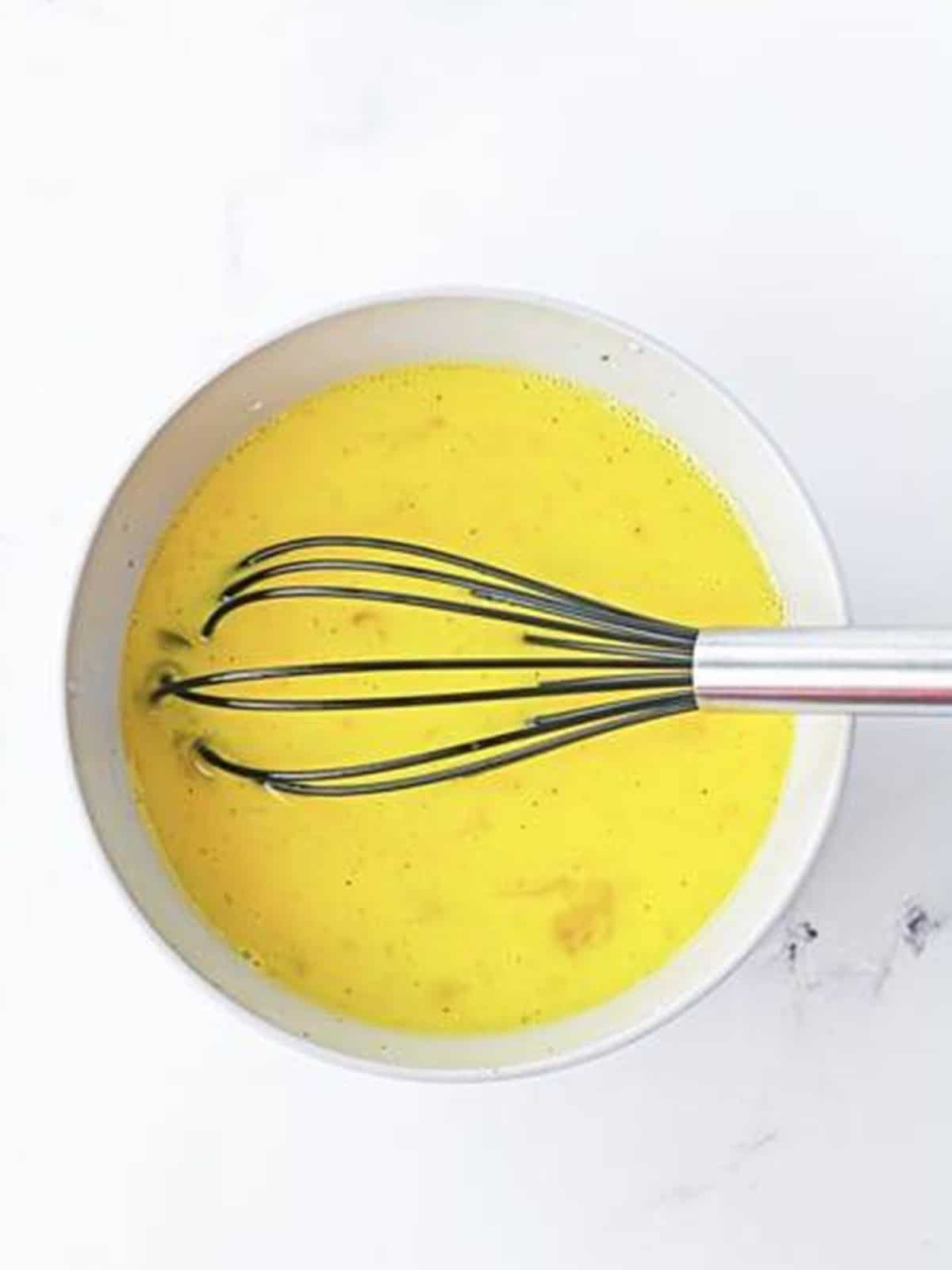 Eggs, milk, salt, and pepper whisked together in a bowl for breakfast sliders.