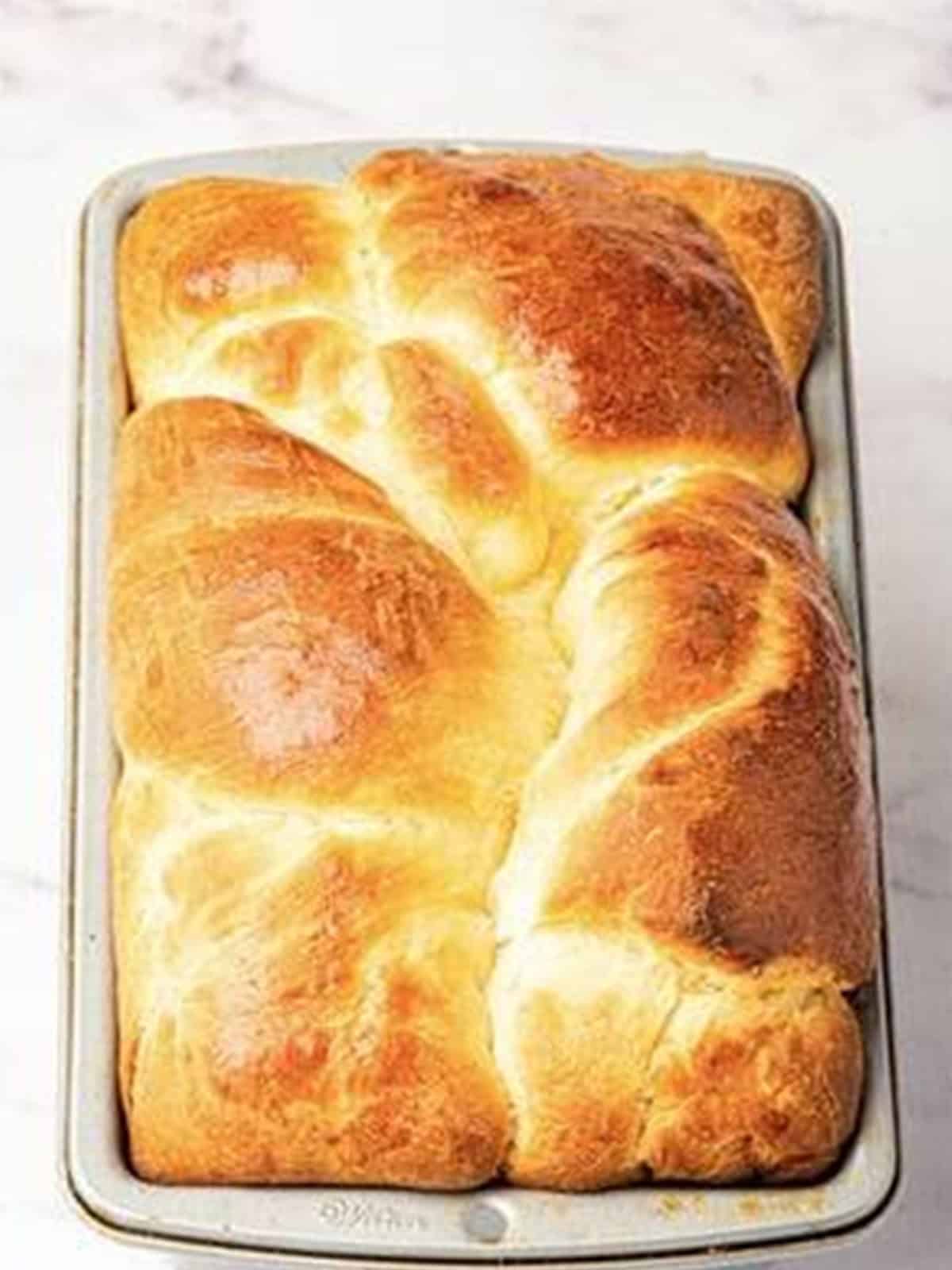 A finished deeply golden brown baked brioche bread loaf.