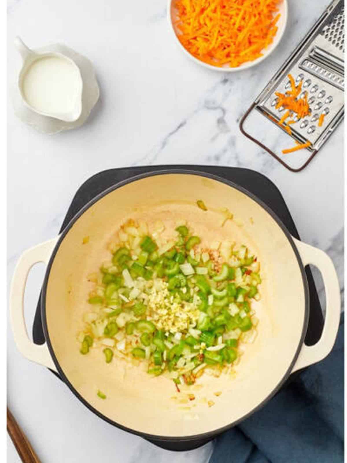 Onion and celery cooking in butter in a pot for broccoli cheddar soup.
