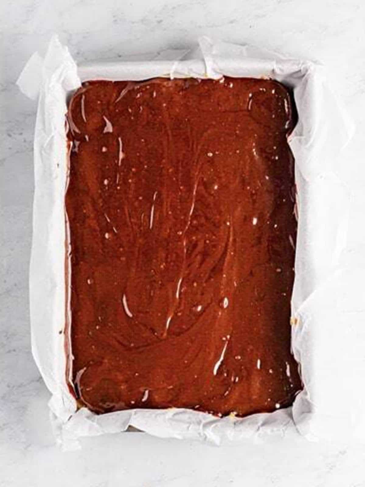 Fudge brownie batter spread over the Oreo layer for Brookies before baking.