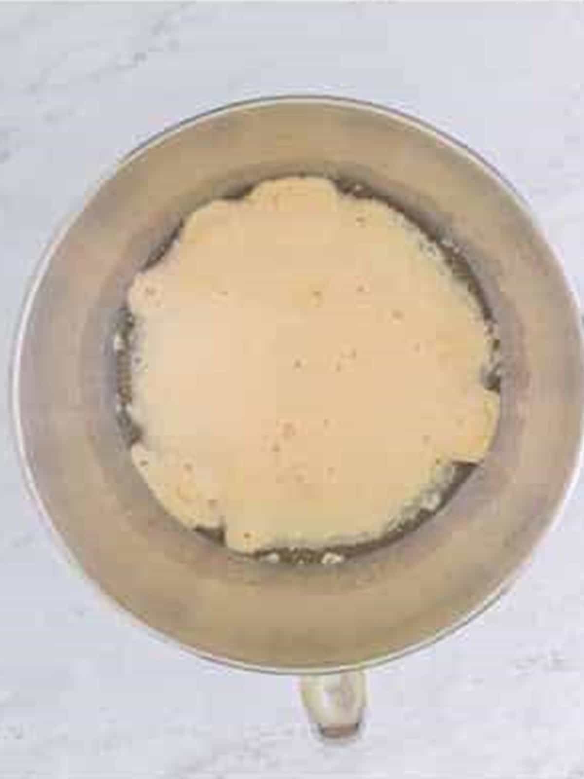 Warm water, yeast, and sugar foaming in a stand mixer bowl for Cheesecake Factory brown bread.