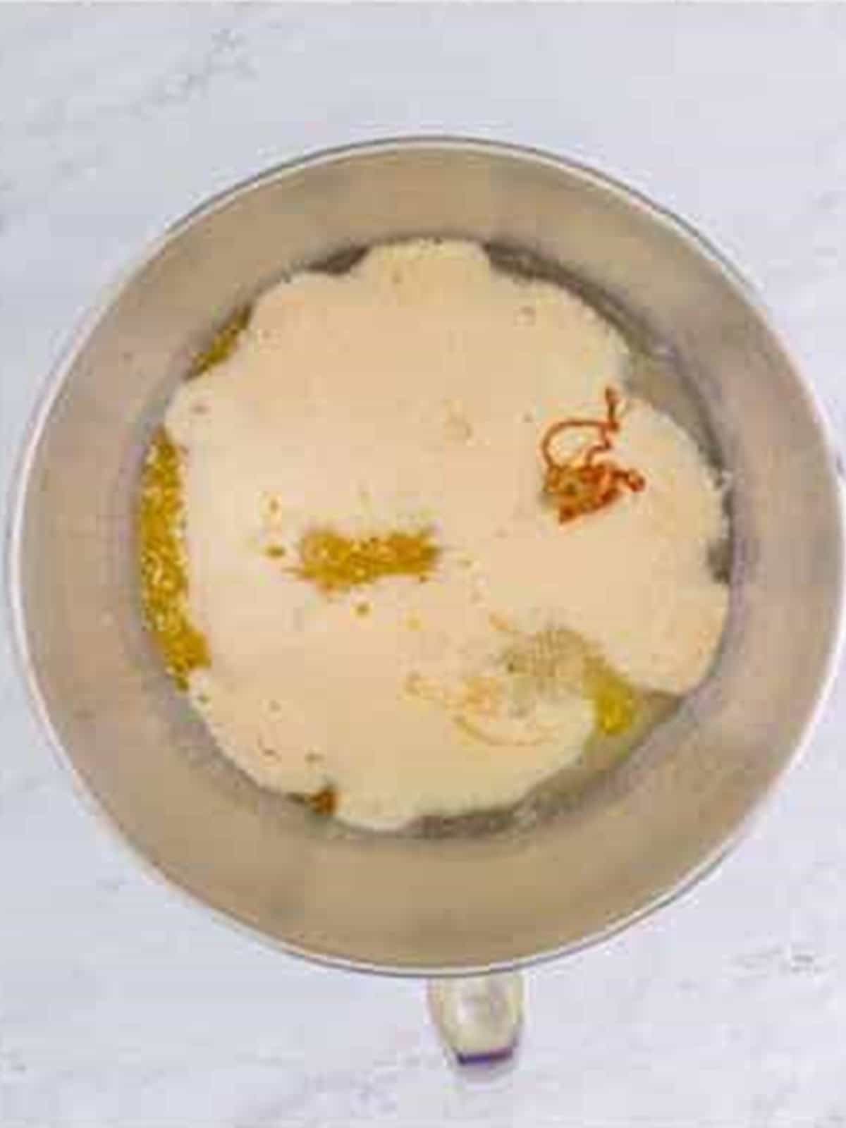 Honey, molasses, and melted butter added to the bubbly yeast mixture in a mixer bowl.