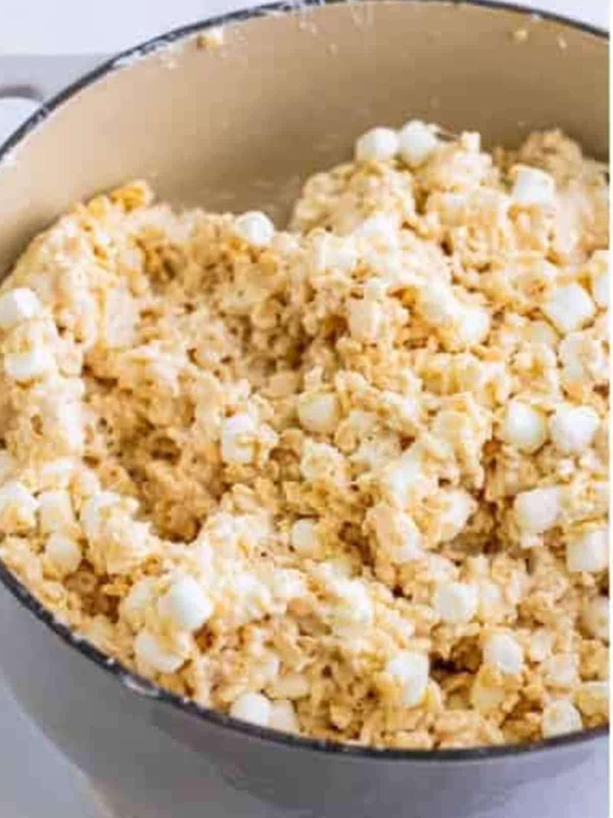 Brown butter rice krispie treat mixture stirred together with pockets of marshmallow.