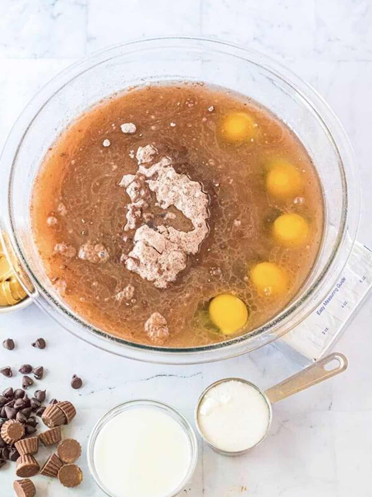 Chocolate cake mix, brownie mix, eggs, and oil combined in a bowl for brownie cake batter.