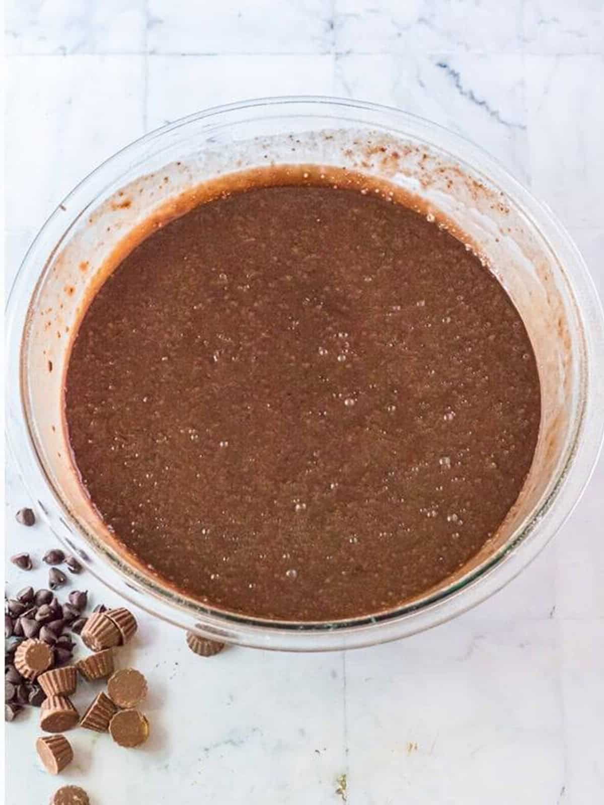 Smooth brownie cake batter mixed in a glass bowl.