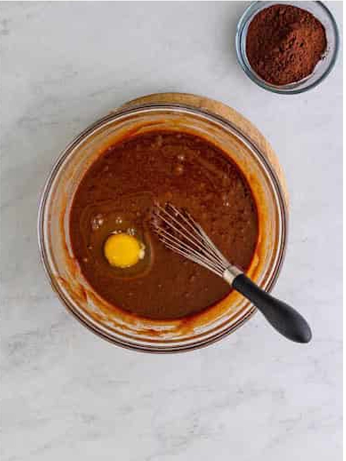 Whisking sugar and eggs into the melted chocolate brownie mixture.