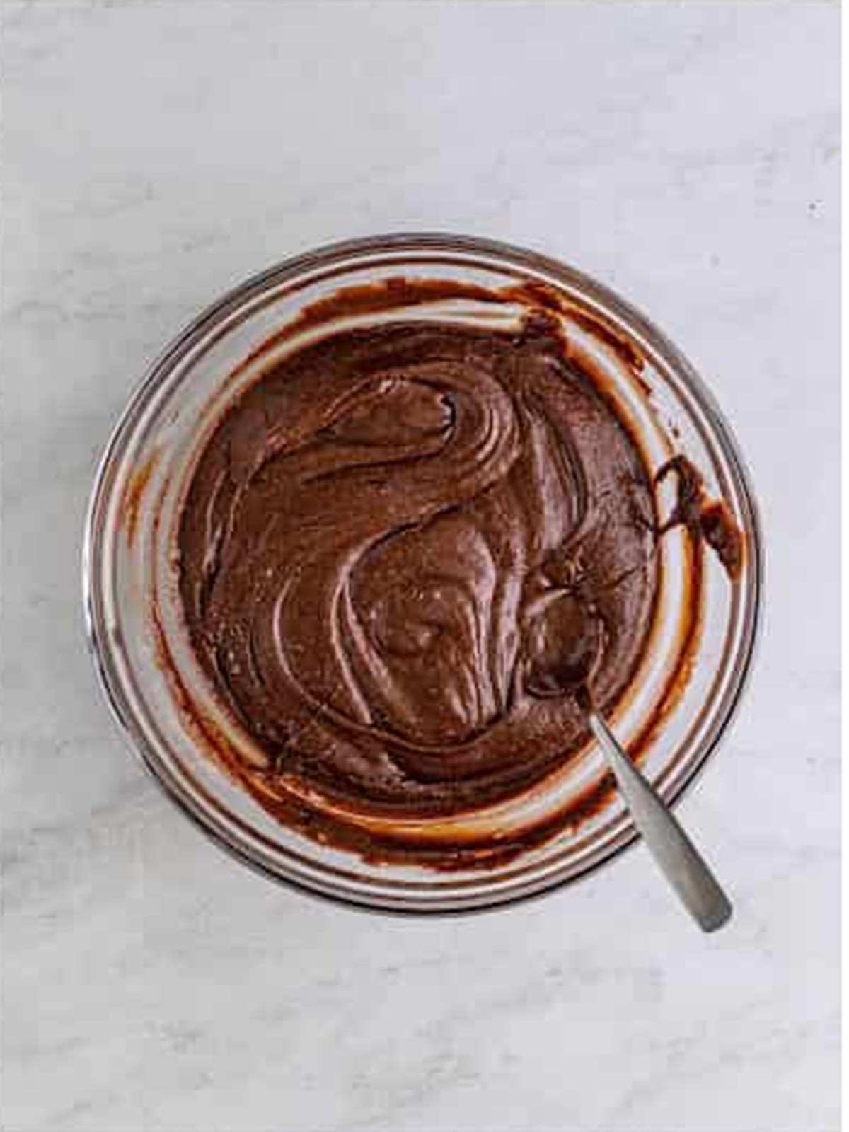 Glossy finished brownie batter in a glass bowl ready to bake.