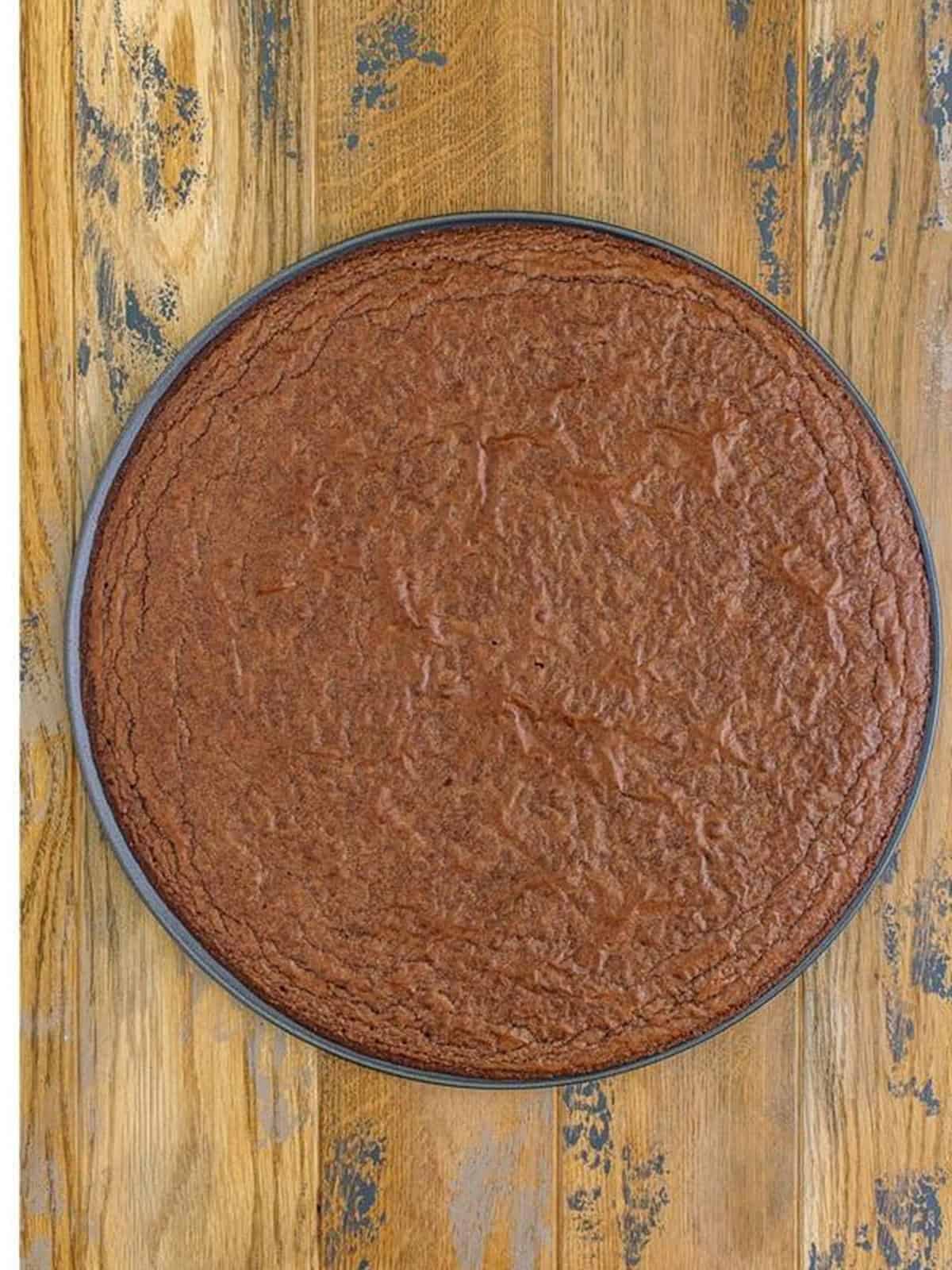 The baked brownie pizza base cooling in the round pan.