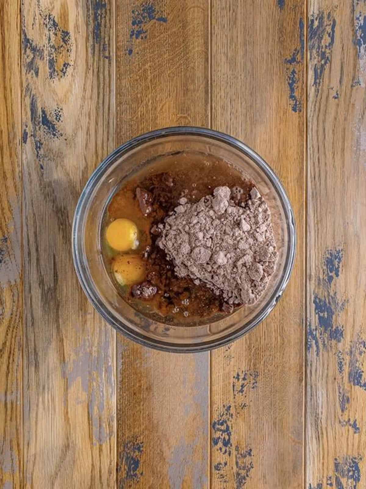 Brownie mix, eggs, oil, and water added to a glass mixing bowl.